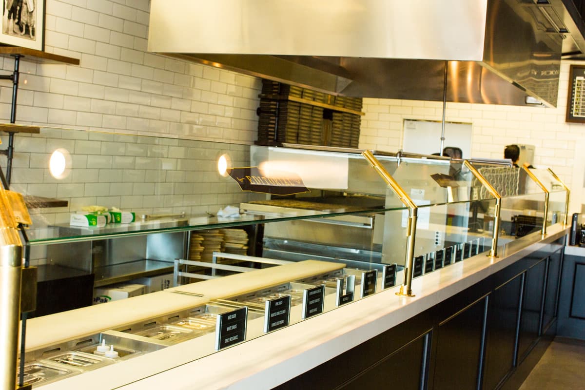 Glass-fronted service line with brass details beneath the kitchen hood